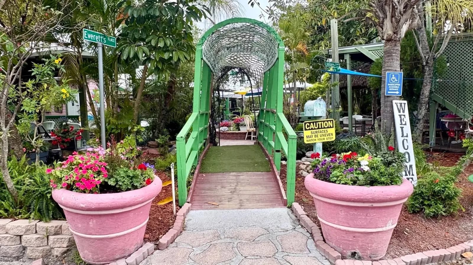 A green footbridge and pink planters at The Chattaway garden entrance.